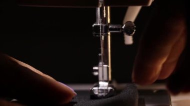 Bir kız dikiş makinesine dikiş dikiyor. Karanlıkta, bir lambanın ışığında dikiş makinesine.