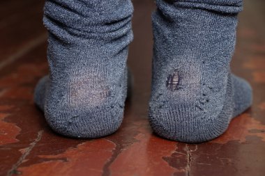 Evin zemininde çorapları yırtık ve yıpranmış kadın bacakları. Yoksulluk ve kir içinde, bacaklarında yırtık çorap.