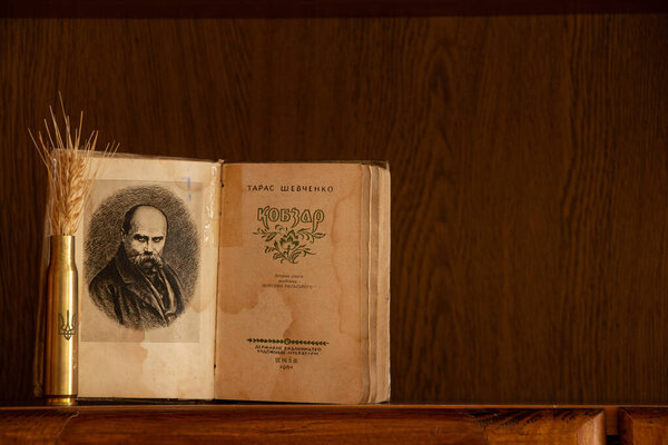 Украина Днепр 09 февраля 2025 года - Книга Кобзаря Тараса Шевченко и гильза с гербом Украины и ухом пшеницы на полке