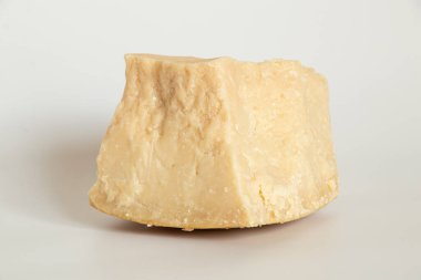 Sert peynirin bir parçası beyaz arka planda yatıyor. Yakın plan, eskimiş sert peynir.