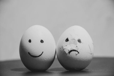 İki tavuk yumurtası, biri neşeyle, diğeri de masada hüzünlü duygularla kırılmış, üzüntü ve keder.