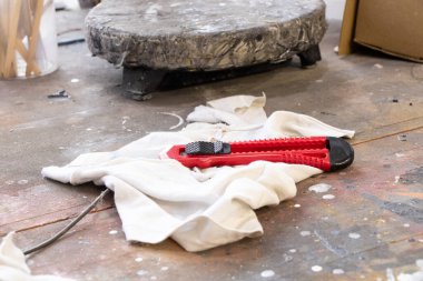 İnşaat bıçağı bir boyacının atölyesinde bir paçavranın üzerinde boyalı bir masa üzerinde duruyor.