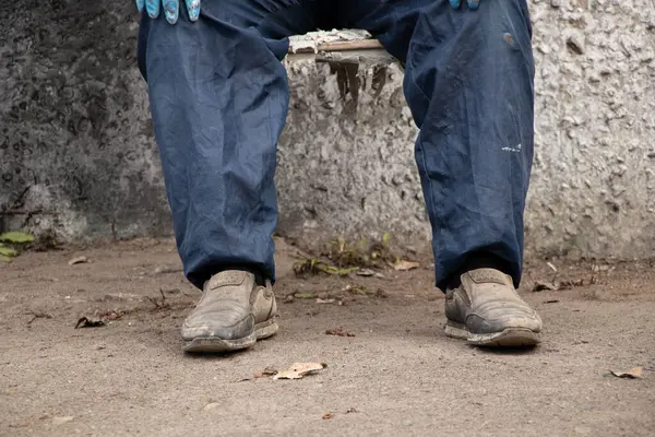 İşçi üniformalı kirli erkek ressam sokakta bir sandalyede oturur dinlenir, kırılır, erkek bacakları kırılır, sıkı çalışır.