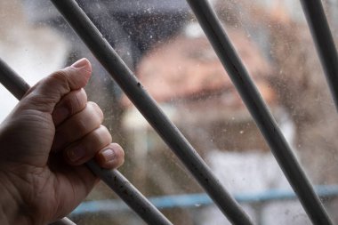 Kadın eli pencerede parmaklıklara tutunuyor özgürlükten, yalnızlıktan yoksun