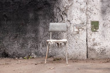 Kirli, yırtık bir sandalye beton duvarın yanında duruyor dinlenmek için dinlenmek için, dinlenmek için