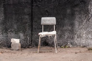 Kirli, yırtık bir sandalye beton duvarın yanında duruyor dinlenmek için dinlenmek için, dinlenmek için