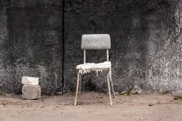 Kirli, yırtık bir sandalye beton duvarın yanında duruyor dinlenmek için dinlenmek için, dinlenmek için