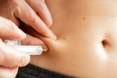 Doktor karnına önceden doldurulmuş şırınga enjekte ediyor. Tedavi, enjeksiyon.