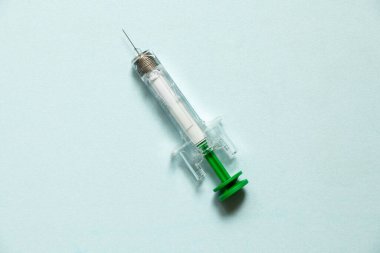 Önceden doldurulmuş şırınga mavi arka planda, iğne, ilaç ve tedavi için şırıngada yatıyor