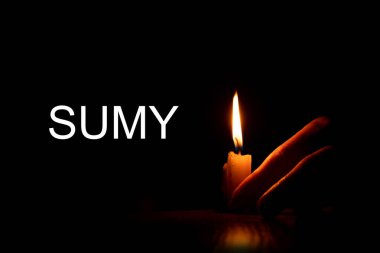 Bir kadının eli mumu tutuyor ve Sumy 'nin siyah bir arkaplanı var. Sonsuz bir anı. Füze saldırısında ölenler için yas tutuyor.
