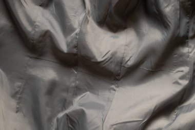 Arka plan olarak dalgalı kıvrımlı gri kumaşlı kadın ceketinde gri ipek astar kumaş.