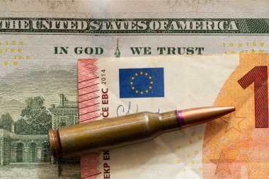 Kurşun dolar ve euro banknotlarında yatıyor, ve dolar banknotundaki metin de güvendiğimiz Tanrı 'ya, silahlar için para diyor.