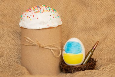 Ukrayna bayrağı taşıyan Paskalya yumurtası, çuval bezinde bir kurşun ve kulich, Ukrayna 'daki savaşta Paskalya.