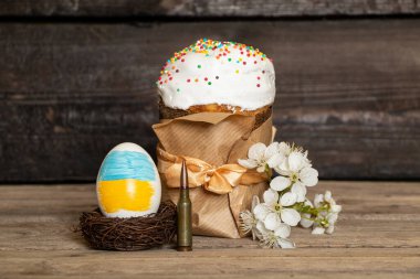 Ukrayna bayrağı boyalı Paskalya yumurtası, kulich ve çiçek açan kiraz dalı ve tahta masa üzerinde kurşun, Ukrayna 'da Paskalya