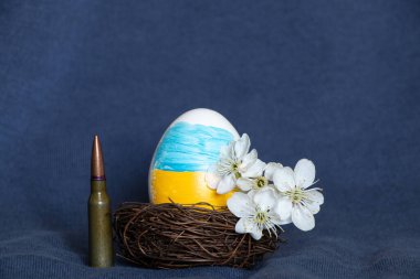 Ukrayna bayrağıyla Paskalya yumurtası, çiçek açan bir dal ve mavi arka planda bir kurşun, Paskalya 'da Ukrayna' da Savaş