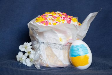 Ukrayna bayrağı boyalı Paskalya yumurtası, kulich ve mavi arka planda çiçek açan kiraz dalı, Ukrayna 'da Paskalya.