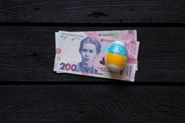 Ukrayna bayraklı Paskalya yumurtası ve kara tahtada 200 Hryvnia faturası, Paskalya harcamaları, harcamalar ve para