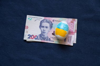 Ukrayna bayraklı Paskalya yumurtası ve mavi kumaşlı 200 Hryvnia banknotu, Paskalya masrafları, harcamalar ve para