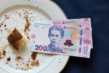 Paskalya pastası, kırıntılı tabaklar ve mavi arka planda 200 Hryvnia banknotuyla yenir. Paskalya masrafları, harcamalar ve para.