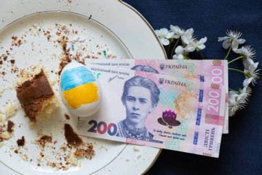 Paskalya pastası, kırıntılı tabaklar ve mavi arka planda 200 Hryvnia banknotuyla yenir. Paskalya masrafları, harcamalar ve para.