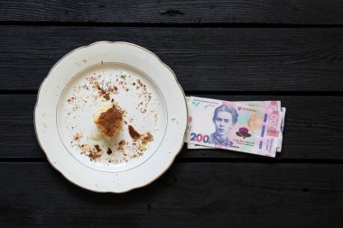 Paskalya pastası tabakta kırıntılar ve kara tahtada 200 Hryvnia banknotları, Paskalya harcamaları, harcamalar ve para ile yenir.