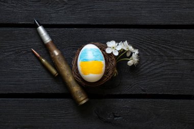 Ukrayna bayraklı Paskalya yumurtası, çiçek açan dal ve kara tahtada kartuşlar, Paskalya 'da Ukrayna' da savaş