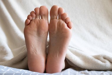 Yatakta uyuyan bir kızın bacakları, evde dinlenen bir kız, kadın bacakları.