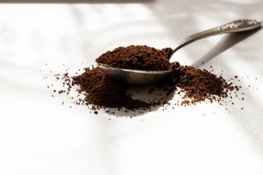 Güneş ışığında öğütülmüş kahveli kaşık, günün başlangıcının kokusu, dağınık öğütülmüş kahve.