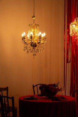 Romantik mum ışığında akşam yemeği, retro avize, masa ve restoranda sandalyeler.