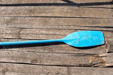 Eski mavi ahşap bir kürek Ukrayna 'da güneşin altında bir ahşap rıhtımda yatıyor.