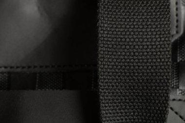 Siyah adamın çantasının kumaş sapı. Arka plan olarak geniş iplikli siyah kumaş.