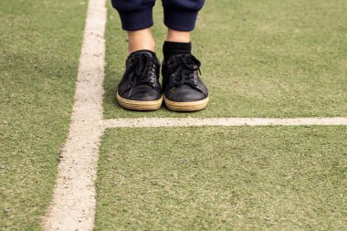 Futbol sahasında siyah spor ayakkabılarla bacaklar, futbol oynamak.
