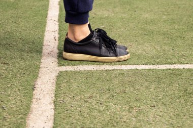 Futbol sahasında siyah spor ayakkabılarla bacaklar, futbol oynamak.