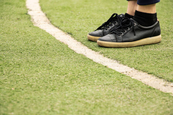 Ноги в черных кроссовках на линии зеленого футбольного поля, играть в футбол, спорт