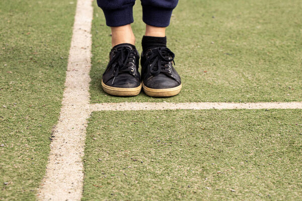 Ноги в черных кроссовках на футбольном поле с метками, играть в футбол