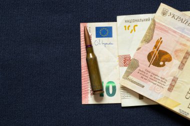 10 euro ve 100 hryvnias ve mavi arka planda bir kurşun, destek konsepti, savunma ve silah için para