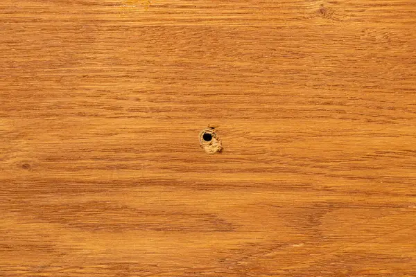 Ahşap yüzeyde delik, mobilya tamir teması için arka plan, tahtanın ortasında delik.