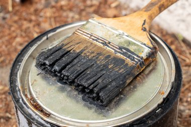 Yerdeki teneke kutuda siyah boya ile fırça, boya, onarım ve bitirme işleri için bir araç