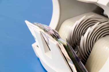 Mavi masasında bir yığın Ukrayna hryvniası olan para sayma makinesi, faturaları sayma süreci, sayma makinesi.