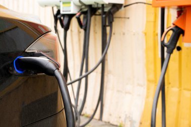 Ukrayna Dnipro 05 / 28 / 2025 - Tesla elektrikli otomobili şarj sırasında bir elektrik dolum istasyonunda hızlı şarj kablosuna bağlandı