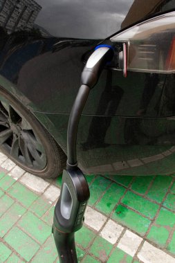 Ukrayna Dnipro 05 / 28 / 2025 - Tesla elektrikli otomobili şarj sırasında bir elektrik dolum istasyonunda hızlı şarj kablosuna bağlandı
