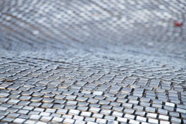Metal küpleri parlak karoların soyut arkaplanı dalgalı bir desen içinde serpiştirilir.