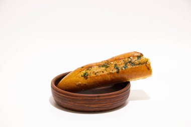 Beyaz arka planda ahşap tabakta ısırılmış otlu aromatik sarımsaklı ekmek.