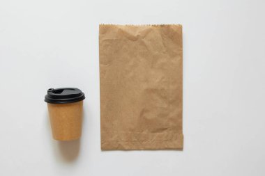 Kağıt torba ve beyaz arka planda kapağı olan kahve fincanı, paket kahve ve yiyecek paketleme modeli, üst görünüm.