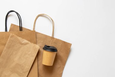 Kağıt torbalar ve beyaz arka planda kapaklı kahve fincanı, kahve ve yiyecek için ambalaj modeli, üst manzara.