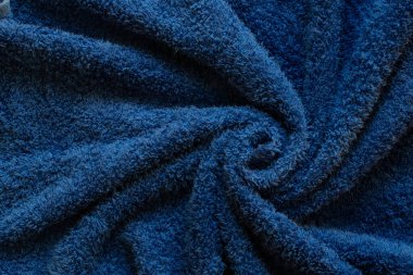 Terry mavi havlusu sarmal bir yakın çekim, yumuşak kumaş dokusu, rahat pamuklu kumaş.