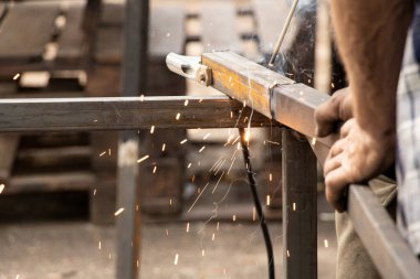 Metal parçaları kıvılcım ve dumanla kaynaştırmak - kaynakçıların elle kaynak yaparak metal elementleri birleştirmesi.