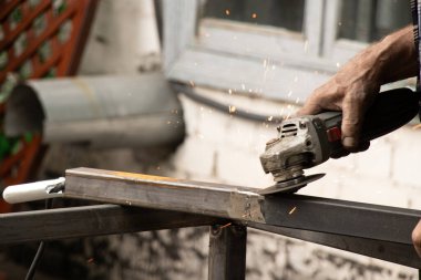 Metal yapıları öğütücüyle öğütmek, dışarıda kaynak yaptıktan sonra eklemler üzerinde çalışan bir usta.