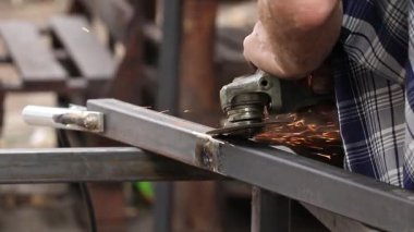 Metal yapıları öğütücüyle öğütmek, dışarıda kaynak yaptıktan sonra eklemler üzerinde çalışan bir usta.
