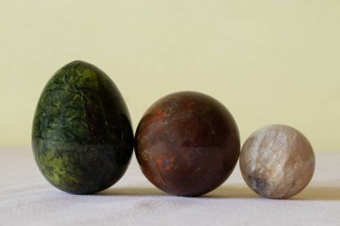 Ay taşı, kuvars ve Jasper zümrüt yumurta şeklinde ve kahverengi-kırmızı bir top şeklinde sarı bir arkaplanda, değerli taşlar, koleksiyon.